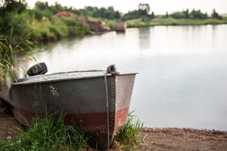 A motor boat is parked at the shore of a lake or river in the evening at sunset or early in the...