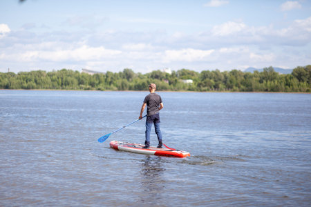 SUP board Stand up paddle man boarding on lake standing happy on blue water. A man swims and rests...