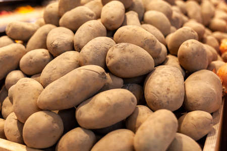 A big pile of fresh potatoes on the counter of a grocery store. Buying vegetables and food for cooking.の写真素材
