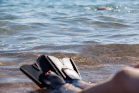 A woman in black flippers splashes near the shore. Fins stick out of the water. swimming equipment....