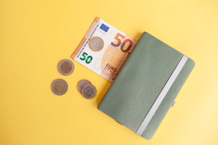 Fifty euro banknotes inside a black wallet on yellow backgroundの写真素材