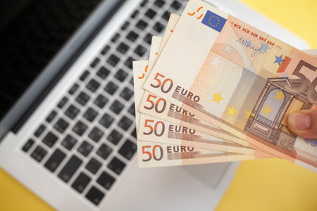 Fifty euro banknotes inside a black wallet on yellow backgroundの写真素材