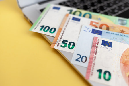 Different Euro bills on a laptop background and on a yellow backgroundの写真素材