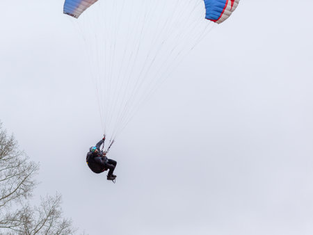 Skydiving extreme sports- parachutist with a parachute unfolded. The sportsman flying on a paraglider. Beautiful paraglider in flight on a light background.の写真素材