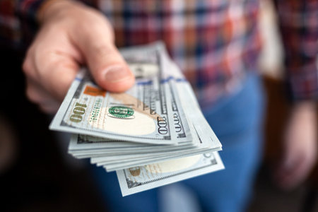 Close up male hand Counting and holding money us dollar. The concept of financial business and crisis.の写真素材
