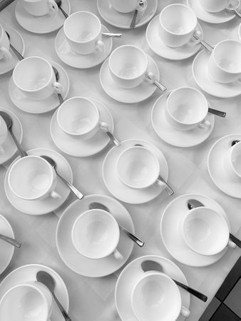 Many rows of white ceramic coffee or tea cups. Lines of coffee cups in the front of the conference room. White ceramic cups and saucers laid out on a buffet table at a catered event for serving a hot beverageの写真素材
