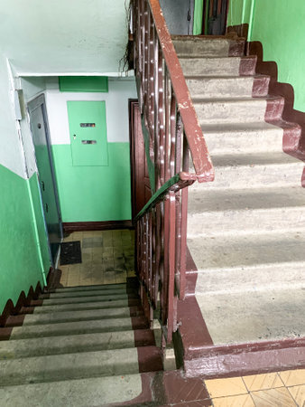 An old Soviet staircase and an entrance in a high-rise building. Concrete staircase in the entrance of an old multistory building. Dirty gray stairs and green walls. Low angle bottom view.の写真素材