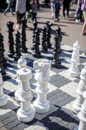 Outdoor chess board with big plastic pieces. Giant size chess in public area zone. Close up big pieces and giant chess board of street chess in the parkの写真素材