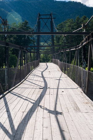 A wooden bridge with metal supports across a raging riverの写真素材