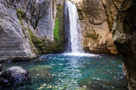 A beautiful mountain gorge with a river and a waterfallの写真素材