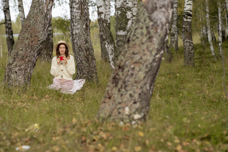 A young beautiful woman in a dress and a round hat reads a bookの写真素材