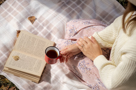A young beautiful woman in a dress and a round hat reads a bookの写真素材