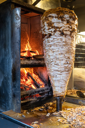 Grilled chicken meat on a vertical rotisserie used in traditional