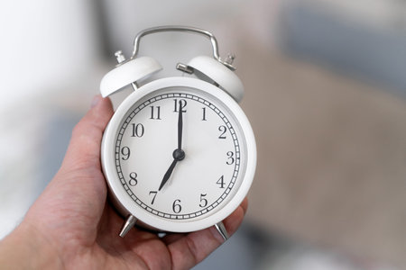 Round white alarm clock in a mans hand close-up.の写真素材