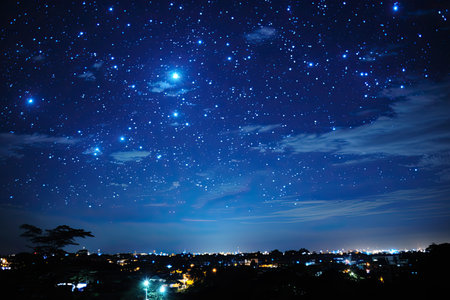 Cosmic stars burn brightly in the night sky. View of the stars with clouds through the trees in the forest or above the city, Generative AIの素材