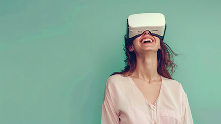 A woman wearing a pink shirt smiles while experiencing virtual reality through a headset on a pastel green background.の素材