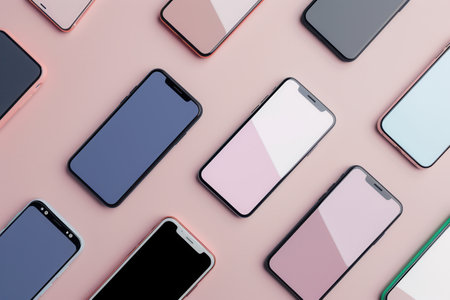 An overhead view of several modern smartphones arranged on a pink background, showing their sleek design and versatility.の素材