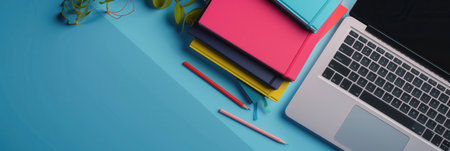 A contemporary image of a laptop and textbooks on a blue desk, showcasing modern learning methods and online education resources.の素材