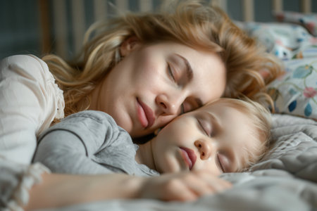 A mother and her child sleep soundly together in a bed, capturing a moment of peaceful rest and connection.の素材