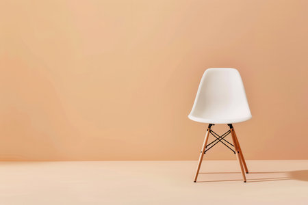 A single white plastic chair with wooden legs sits on a beige background.の素材