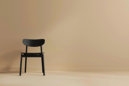 A black chair sits alone on a beige floor in front of a beige wall.の素材
