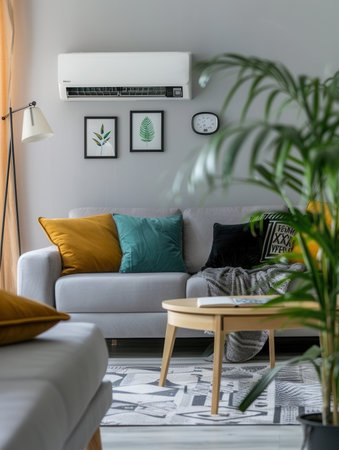 A contemporary living room features a cozy couch, decorative cushions, an air conditioner, and indoor plants adding a refreshing touch to the bright space.の素材
