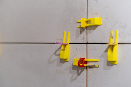 Detailed view of tile leveling system in use with plastic clips and wedges. Essential tools for achieving a flawless finish in tiling projectsの写真素材