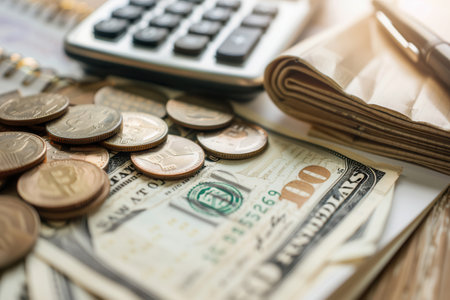 A stack of cash rests next to coins and a notebook filled with notes and calculations, reflecting a personal finance session in a comfortable setting.の素材