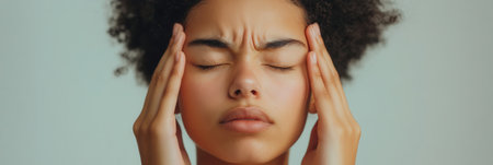 The individual appears deep in thought, hands on their head, conveying feelings of stress and anxiety in a serene atmosphere.の素材