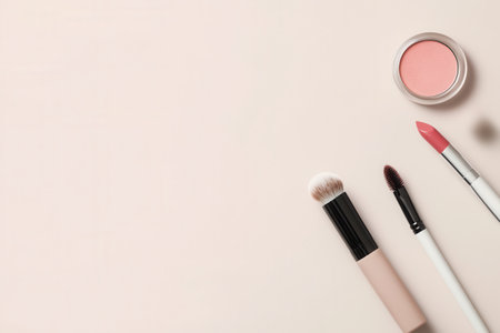 A neatly arranged set of cosmetic products showcases lipstick, brushes, and powder on a soft, light background for beauty lovers.の素材