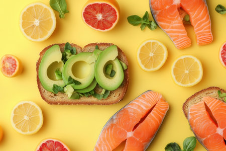 Enjoy a healthy breakfast featuring creamy avocado toast, fresh salmon, and vibrant citrus slices on a cheerful yellow surface.の素材