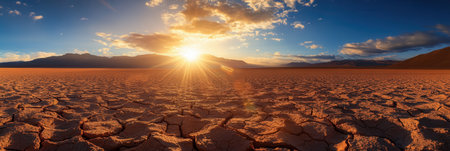 Desert land sprawls under a bright sun, showing casing cracks in the ground as climate change impacts the environment profoundly.の素材