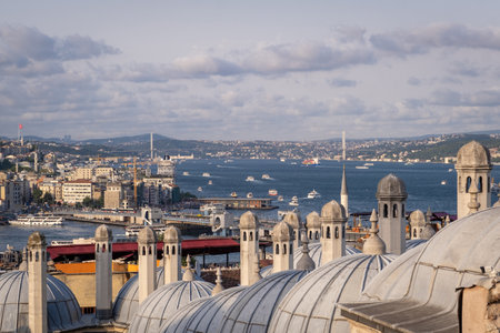 The Bosphorus glimmers as boats navigate its waters, framed by Istanbul's iconic domes under a cloudy sky.の写真素材