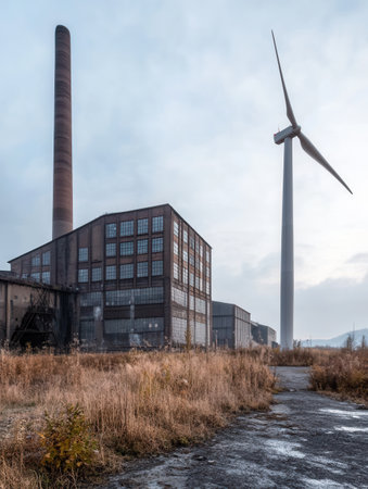 Wind turbines stand tall beside decommissioned factories, showing the shift from coal dependency to renewable energy sources.の素材