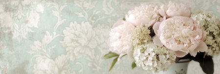 A lovely bouquet of soft-toned peonies and hydrangeas is elegantly arranged in an antique vase, enhancing the charming decor.の素材