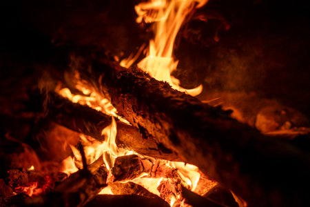 Flames flicker and crackle as they consume wooden logs, providing warmth and ambiance on a chilly night.の写真素材