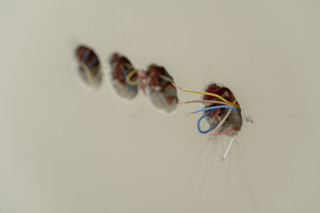 Electrician connects colorful wires into electrical boxes as part of home renovation work on...