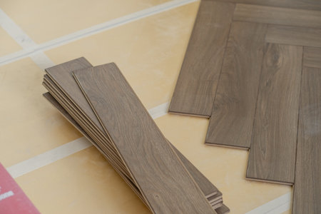 Close-up of laminate flooring installation in a modern apartment. Worker placing wood planks for a smooth and polished home finishの写真素材