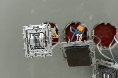 Technicians are seen installing electrical switch plates in wall openings, preparing for the wiring connections.の写真素材