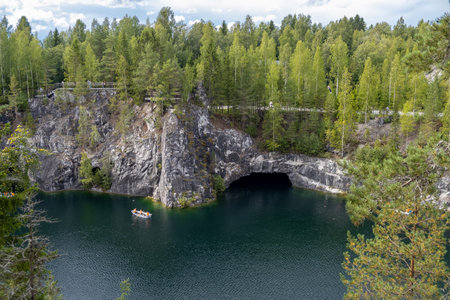 Visitors enjoy the tranquil waters of Marble Canyon, surrounded by lush greenery and striking rock formations in Karelia, Russia.の写真素材