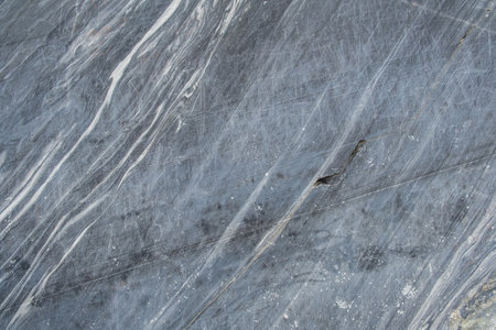 The smooth surface of gray marble features intricate white veining, highlighting its unique patterns ideal for countertops and flooring.の写真素材