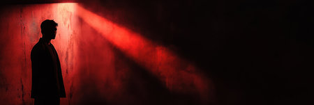 A dark room emphasizes a shadowy figure caught in a spotlight, surrounded by intense black and red hues, evoking a sense of dread.の素材