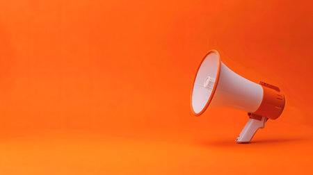 A vibrant orange megaphone stands against a matching backdrop, symbolizing communication and outreach in a minimalist setting.の素材