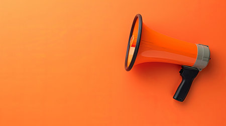 A bright orange megaphone stands against a matching orange backdrop, emphasizing clarity and bold communication.の素材