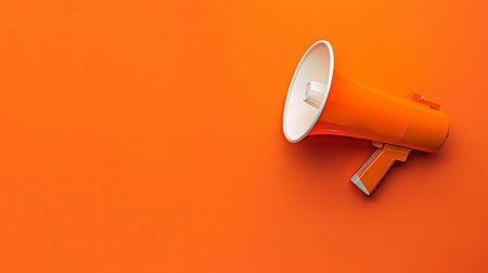 The bright orange megaphone rests against a matching background, ready to amplify voices in public spaces or events.の素材
