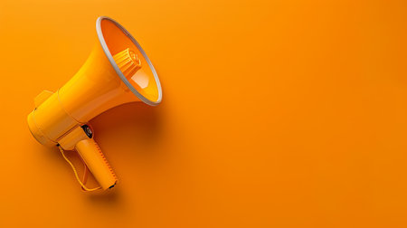 A vibrant yellow megaphone rests against a striking orange backdrop, representing effective communication and lively announcements.の素材