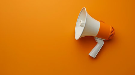 The megaphone, with its striking orange color, sits on a vibrant orange wall, representing a call to action or announcement medium.の素材