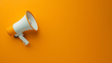 A white and orange megaphone is mounted on an orange wall, ready to be used for making announcements or capturing attention.の素材