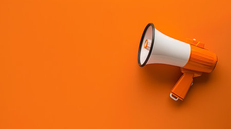 A vibrant orange megaphone rests on a solid orange background, representing the idea of communication and expression.の素材