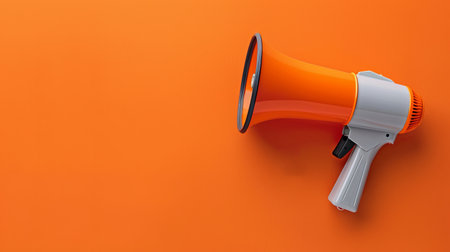 A bright orange megaphone sits on a matching orange background, showing its design and purpose for making clear announcements.の素材